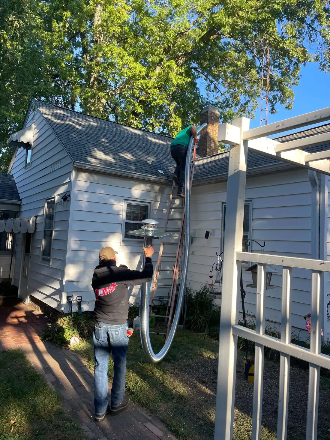 Allied technician guiding a flexible chimney liner up to the rooftop crew