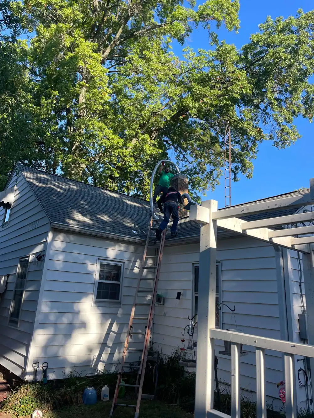 Allied technicians on a rooftop feeding a new chimney liner into a Springfield home's flue