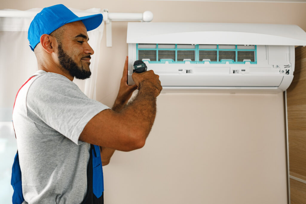 How to Fix an AC That Keeps Tripping Your Circuit Breaker in Chatham 3 Technician installing or repairing a wall-mounted air conditioning unit, emphasizing HVAC service expertise.