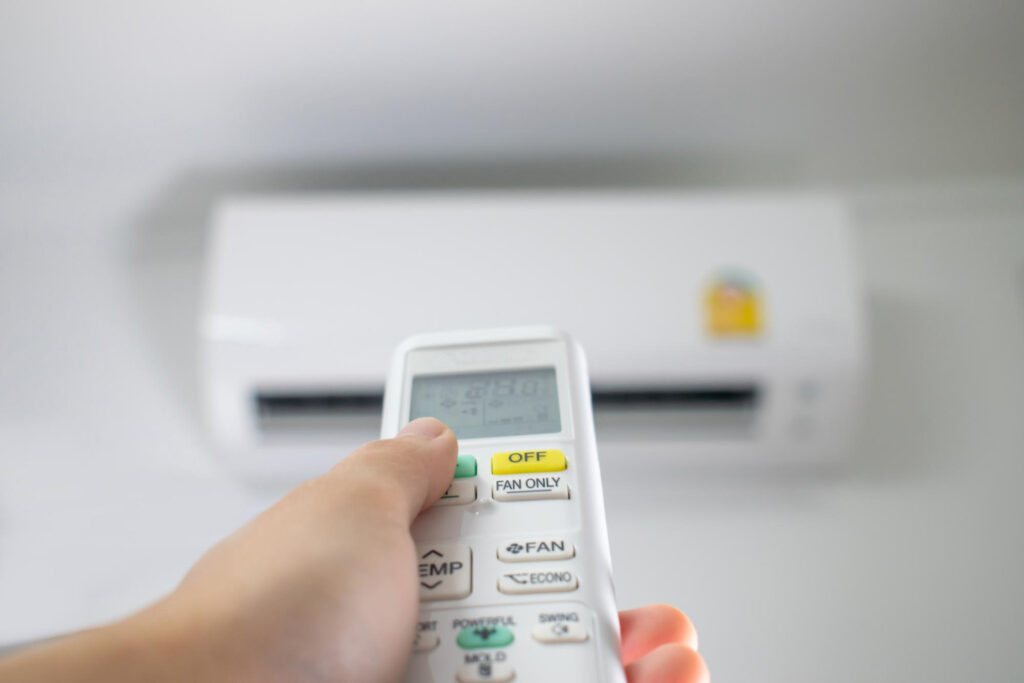Why Your Mini Split AC Is Displaying Error Codes in Sherman 8 Hand holding remote control for mini split AC unit, adjusting settings for optimal HVAC performance.